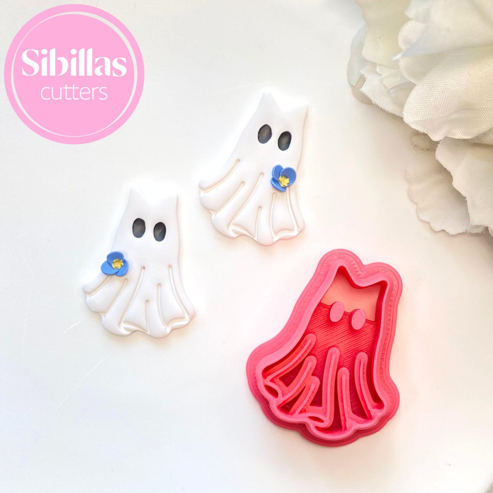 Ghost-shaped cookie cutters with a red mold on a white background