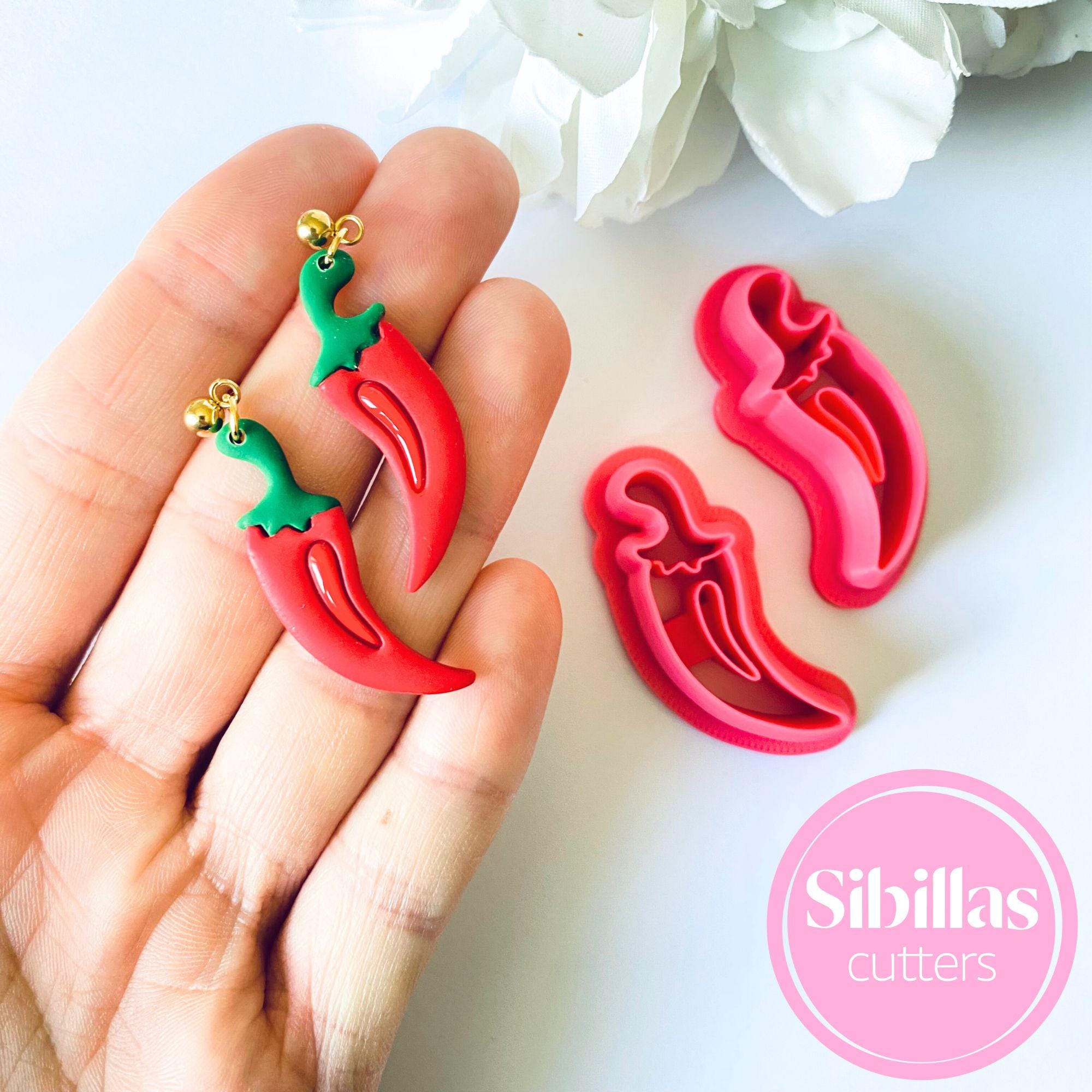 Red chili pepper-shaped cookie cutters held in a hand with a white background and 'Sibillas cutters' branding.