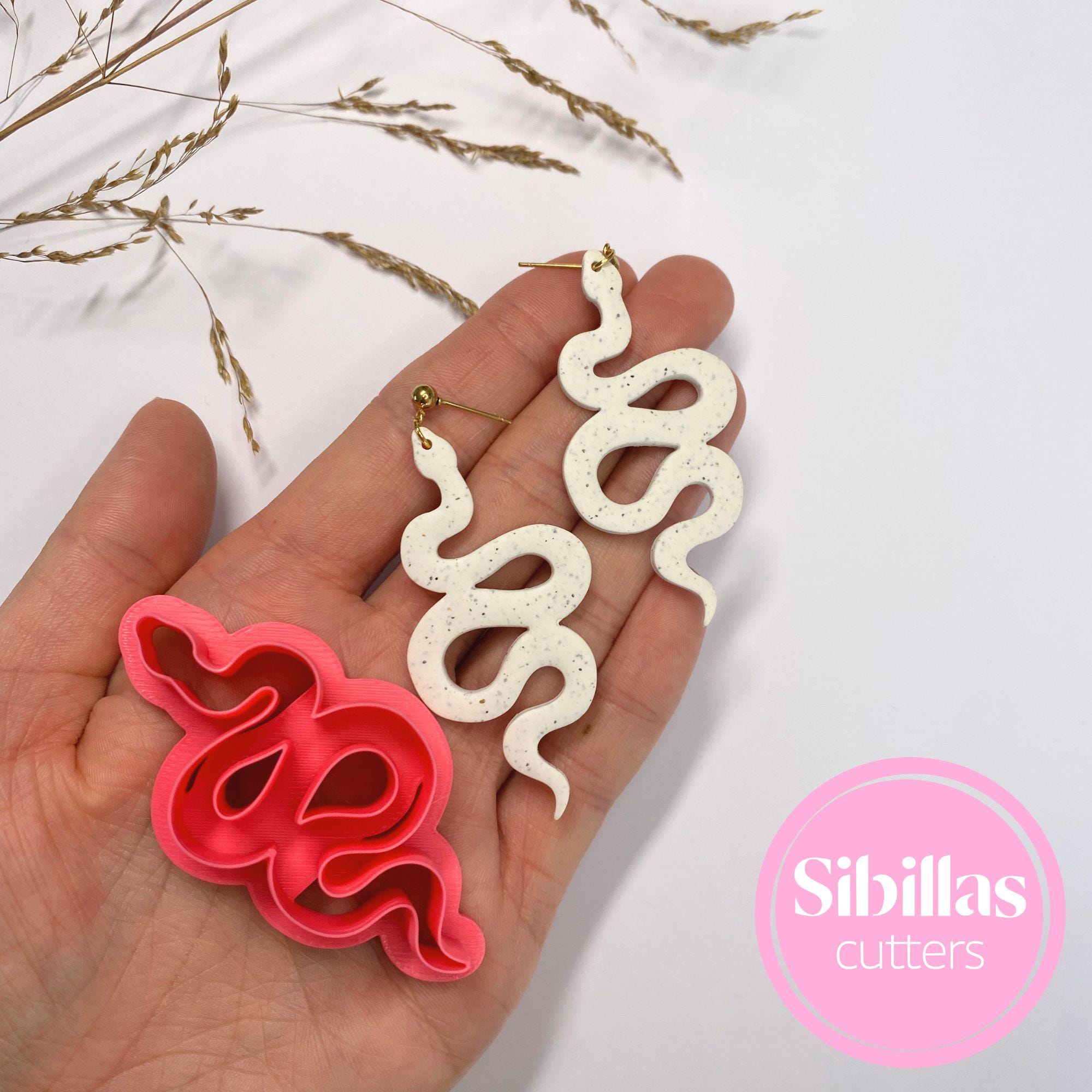 Hand holding snake-shaped cookie cutters with 'Sibillas Cutters' branding.