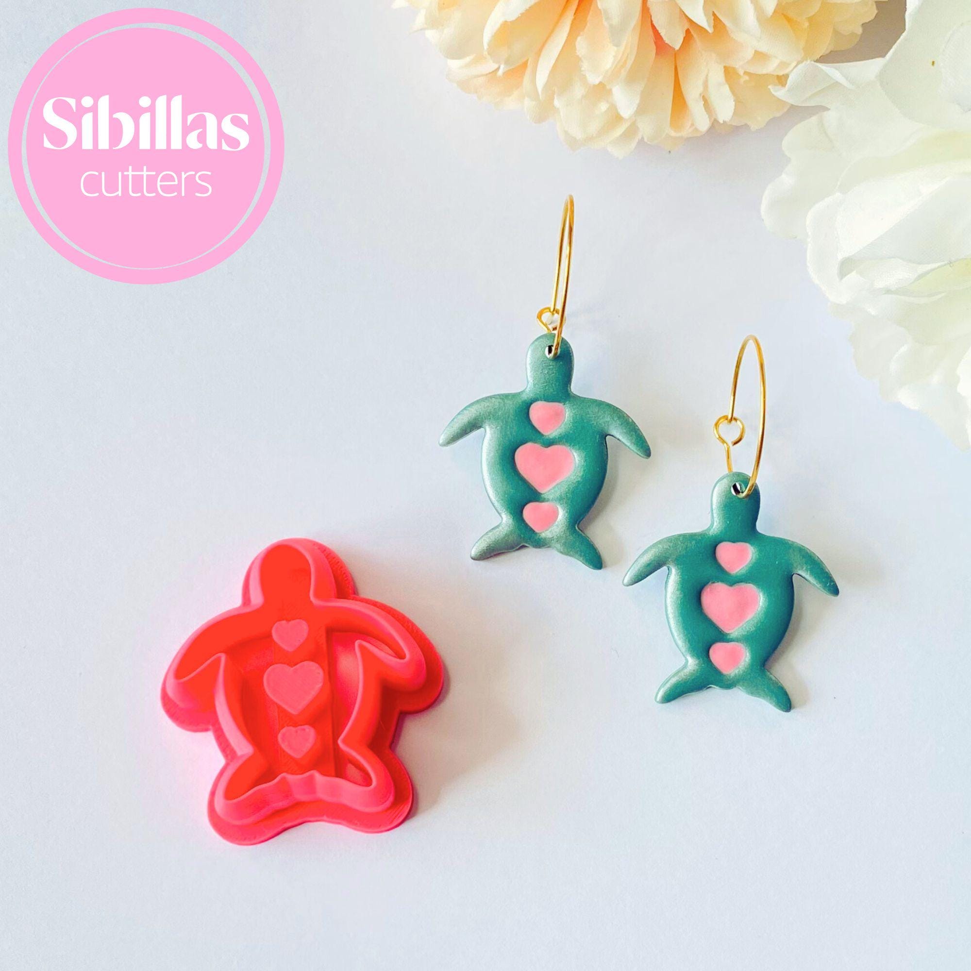 Two green turtle-shaped cookie cutters with pink hearts on a white background, branded 'Sibillas cutters'.